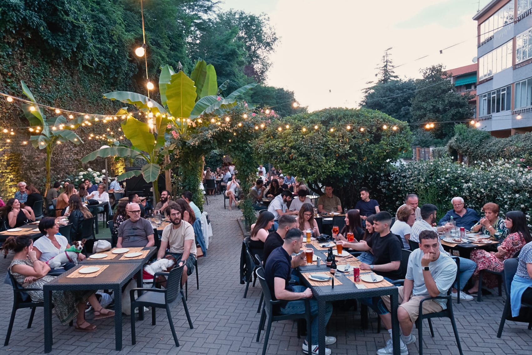 Il giardino di Cittadella Parma pieno di gente ai tavoli sotto le luci, di sera