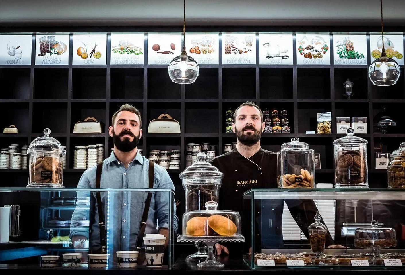 Alberto e Giacomo Banchini dietro il banco della Cioccolateria Banchini a Parma, fra le campane di vetro e gli scaffali scuri