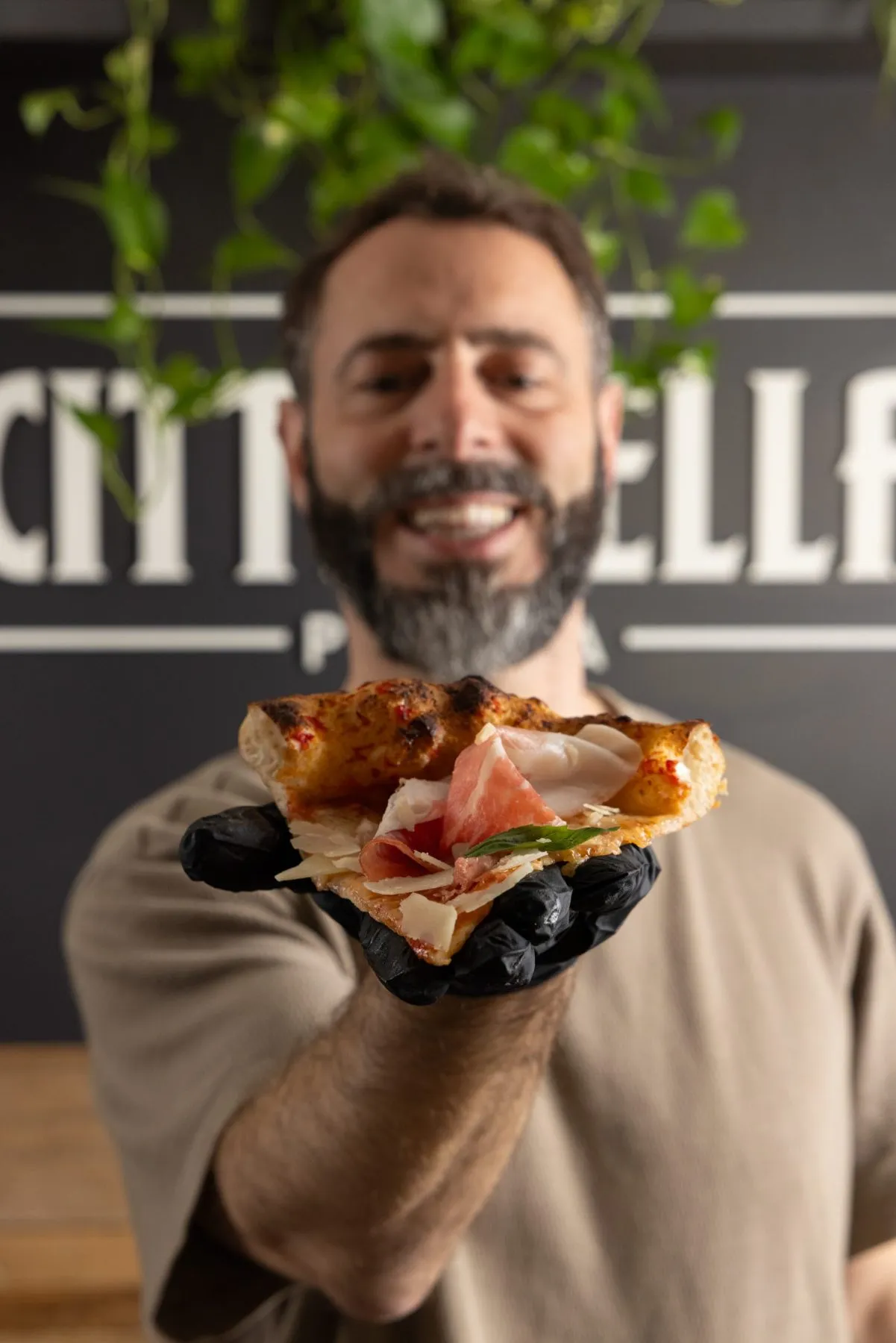 Alberto Banchini sorridente con una fetta di pizza di Cittadella Parma